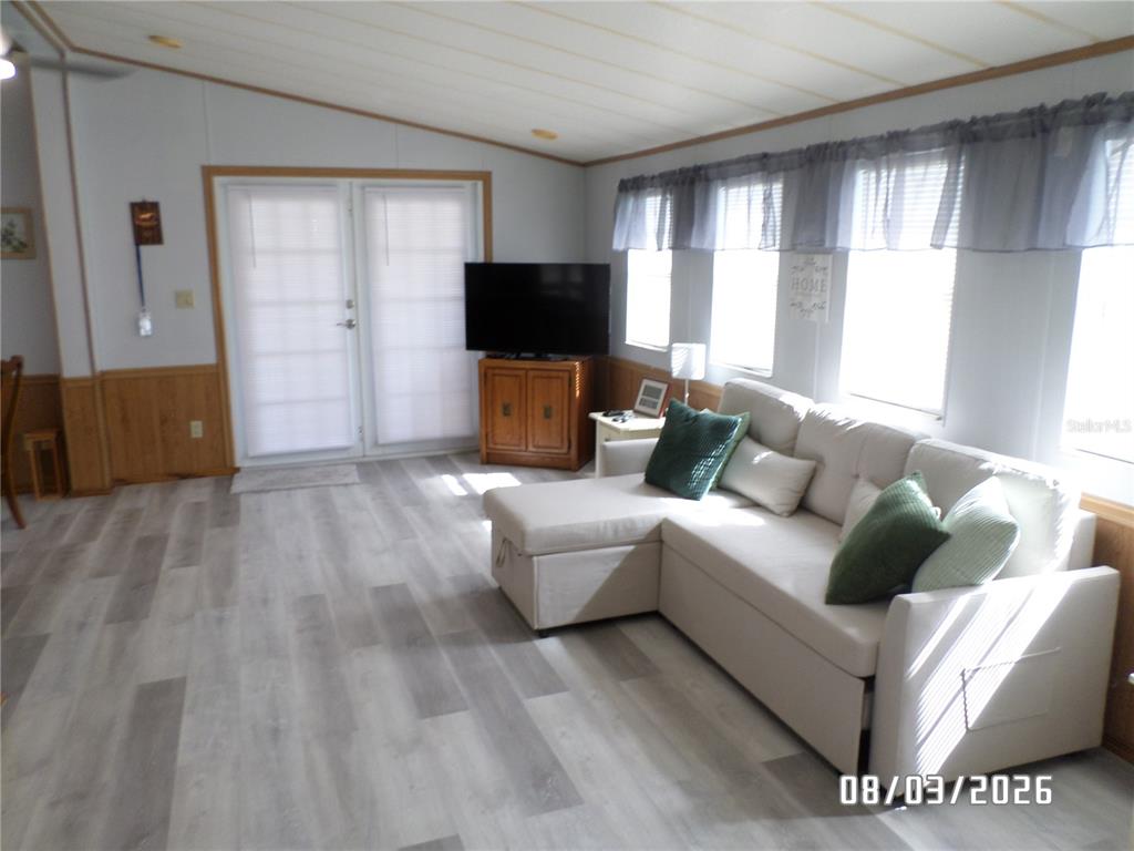 A living room features light wood-look flooring, a sectional sofa, and a television on a cabinet — 83 ROAN ROAD, LAKE WALES, FL