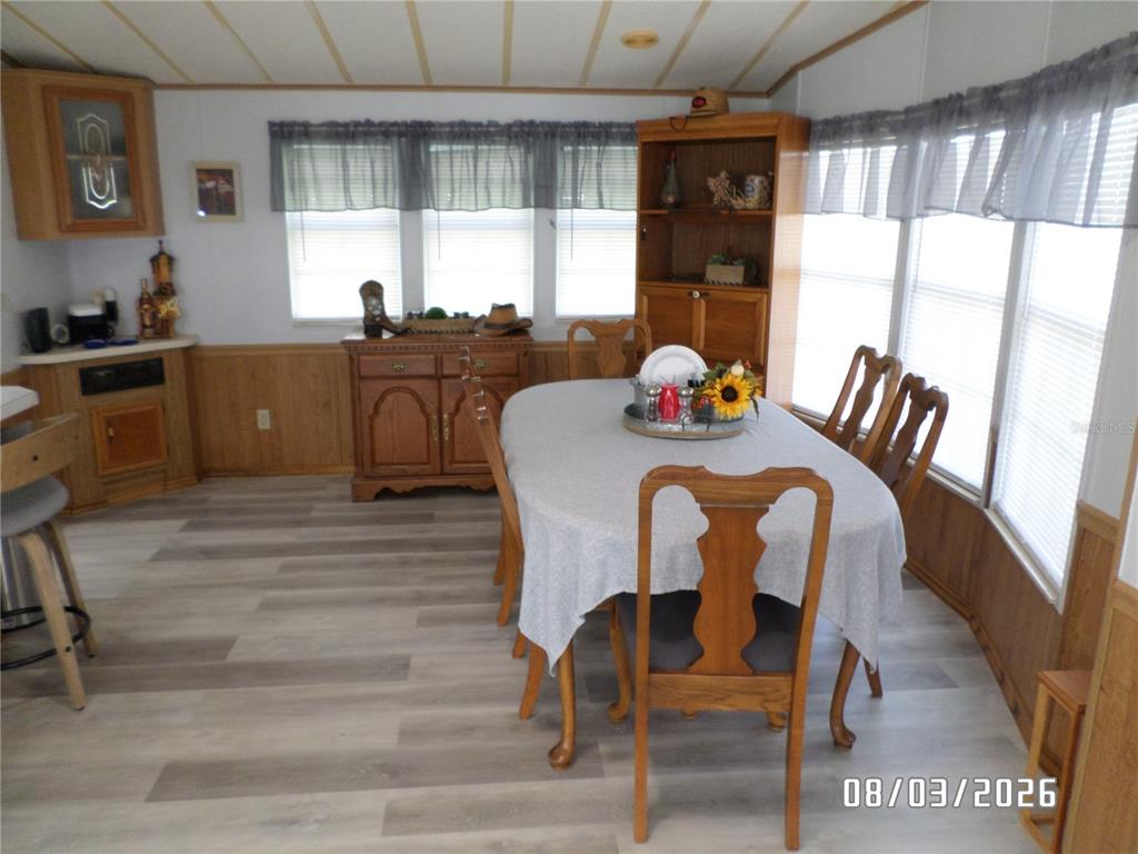 A dining room features wood-paneled walls, light wood-look flooring, a wooden hutch, and a table — 83 ROAN ROAD, LAKE WALES, FL