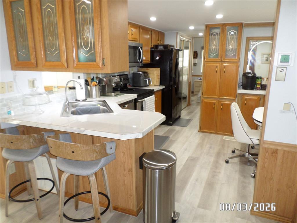 A kitchen features wood cabinets, a white countertop, a stainless steel sink, and bar stools — 83 ROAN ROAD, LAKE WALES, FL