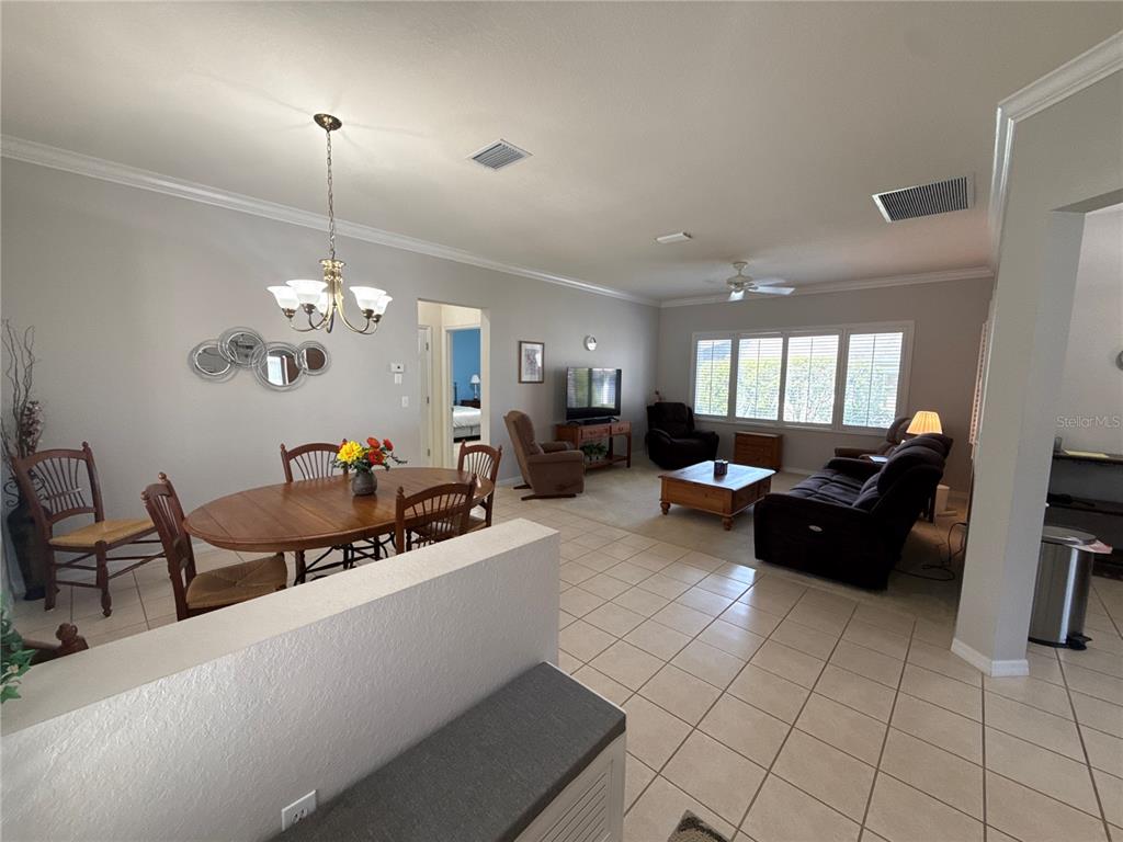 An open-concept living and dining area features tile flooring, a chandelier, and neutral walls — 9484 SE 124TH LOOP, SUMMERFIELD, FL