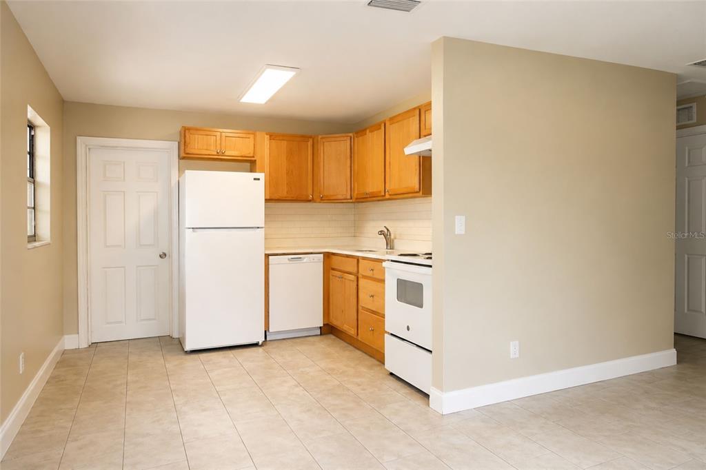 A kitchen with light-colored tile flooring, wooden cabinets, and white appliances — 9412 N ELMER STREET, TAMPA, FL