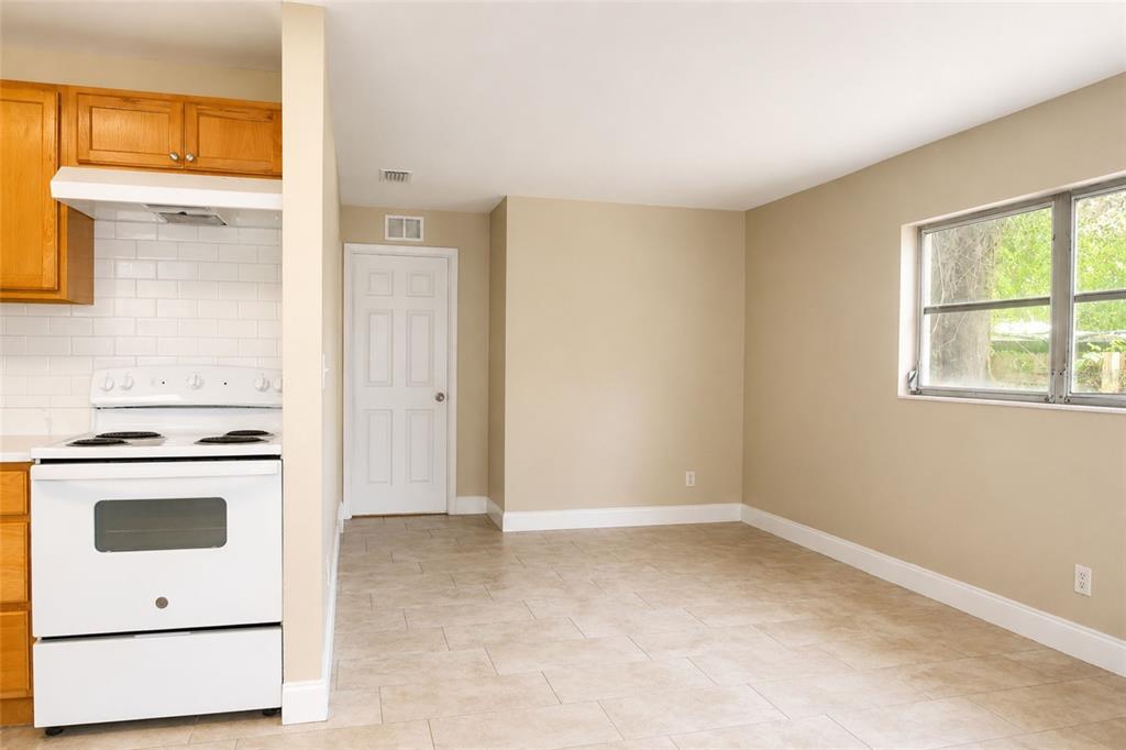 A kitchen area with white appliances, light tile flooring, and beige walls near a window — 9412 N ELMER STREET, TAMPA, FL