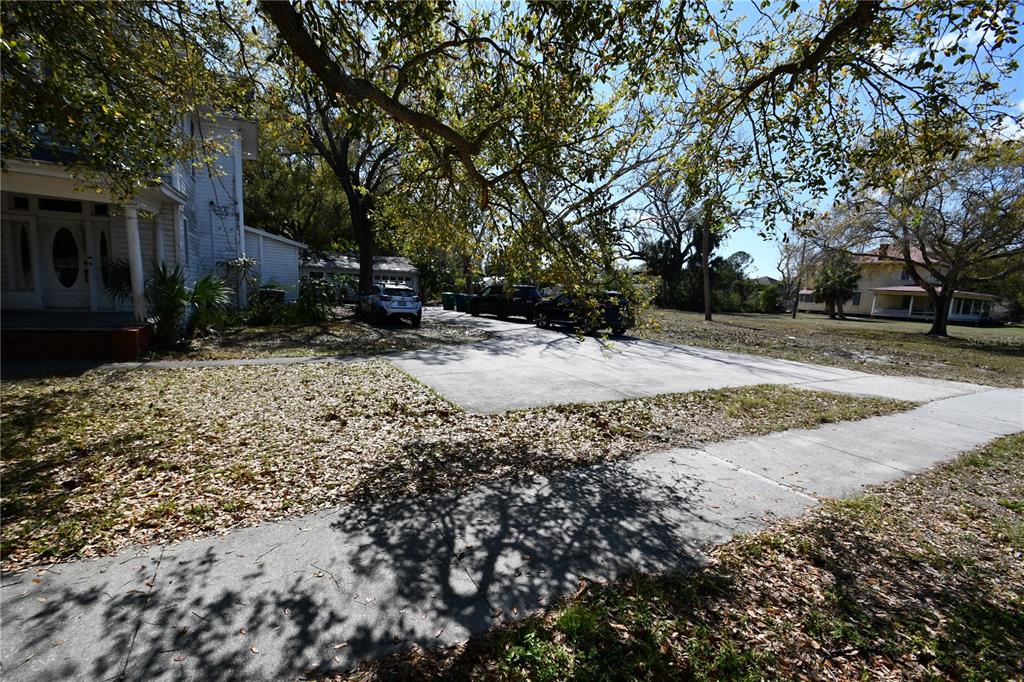 A concrete driveway leads to a white house with a porch under large oak trees — 8020 INTERBAY BOULEVARD, TAMPA, FL