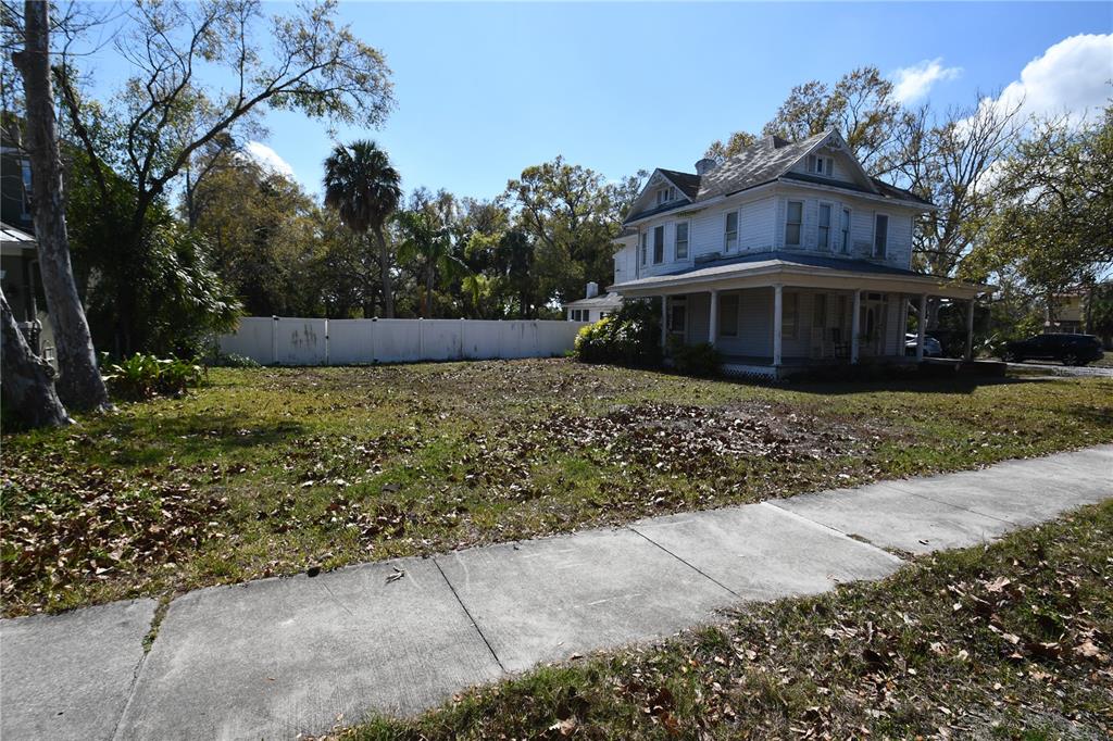 A two-story white house with a wrap-around porch sits behind a large, leaf-covered yard — 8020 INTERBAY BOULEVARD, TAMPA, FL