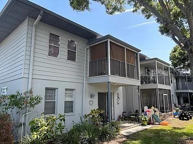 A two-story residential building features light gray siding, screened balconies, and a grassy yard — 10800 US HIGHWAY 19 N UNIT 237, PINELLAS PARK, FL
