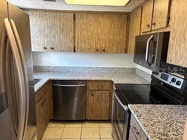 A kitchen features wood cabinets, granite countertops, and stainless steel appliances — 10800 US HIGHWAY 19 N UNIT 237, PINELLAS PARK, FL