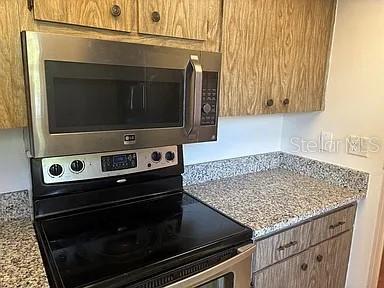 A kitchen features a stainless steel microwave above a black electric range and speckled countertops — 10800 US HIGHWAY 19 N UNIT 237, PINELLAS PARK, FL