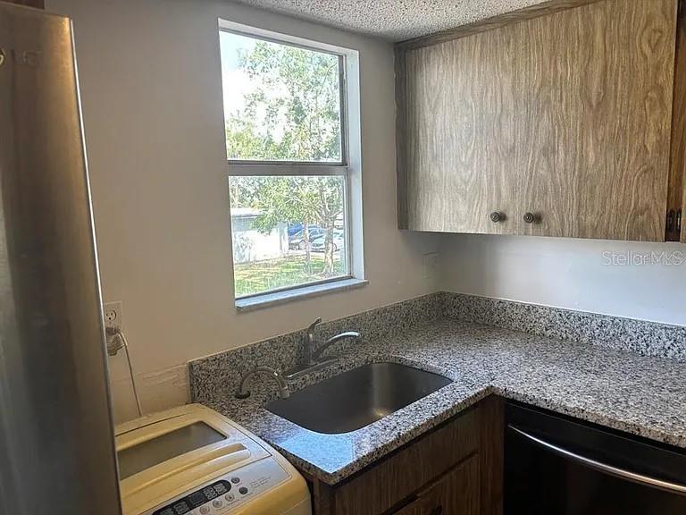 A kitchen features a stainless steel sink, granite-style countertops, and wood-grain cabinets — 10800 US HIGHWAY 19 N UNIT 237, PINELLAS PARK, FL