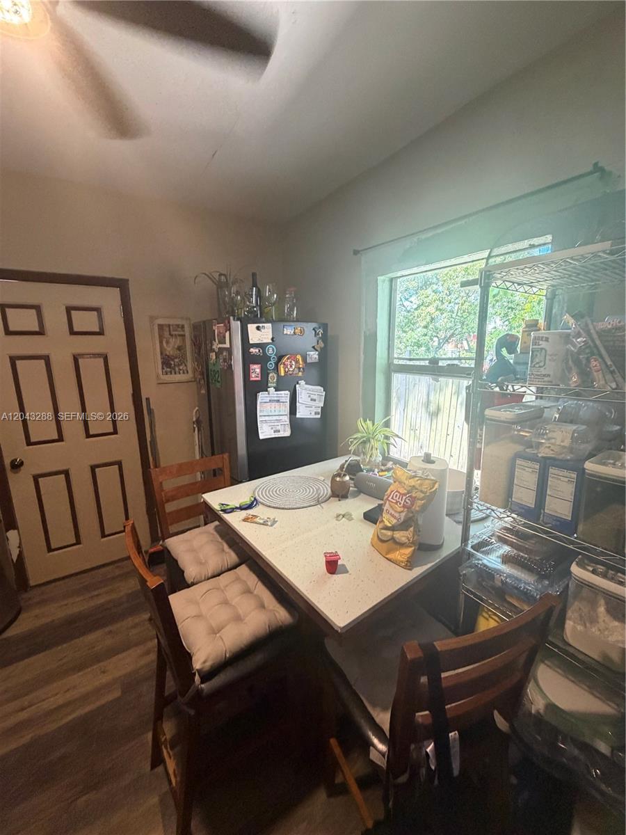 A kitchen features a dining table, chairs, a refrigerator, and a metal storage rack — MIAMI, FL