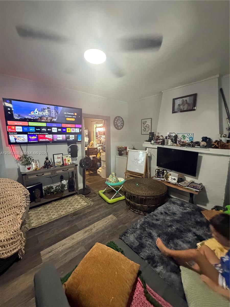 A living room features two televisions, a ceiling fan, a fireplace, and wood-look flooring — MIAMI, FL