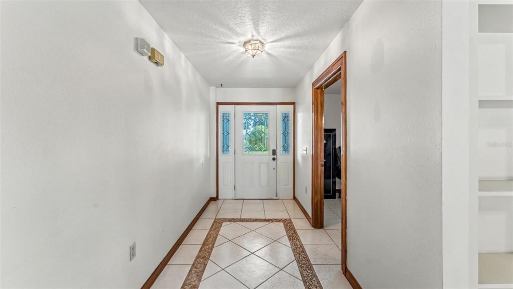 A tiled entryway features a white front door with glass panels and a ceiling light — 14080 US HIGHWAY 98 N, KATHLEEN, FL