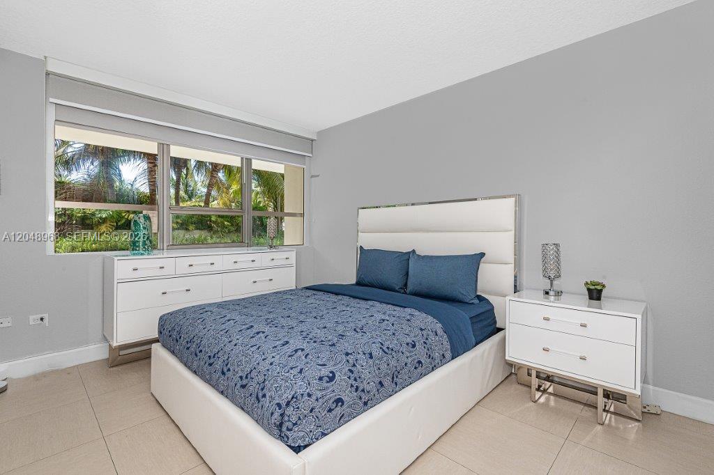 A bedroom features a white bed, matching dresser and nightstand, and a large window — 1500 Bay Rd # 128S, Miami Beach FL 33139, MIAMI BEACH, FL