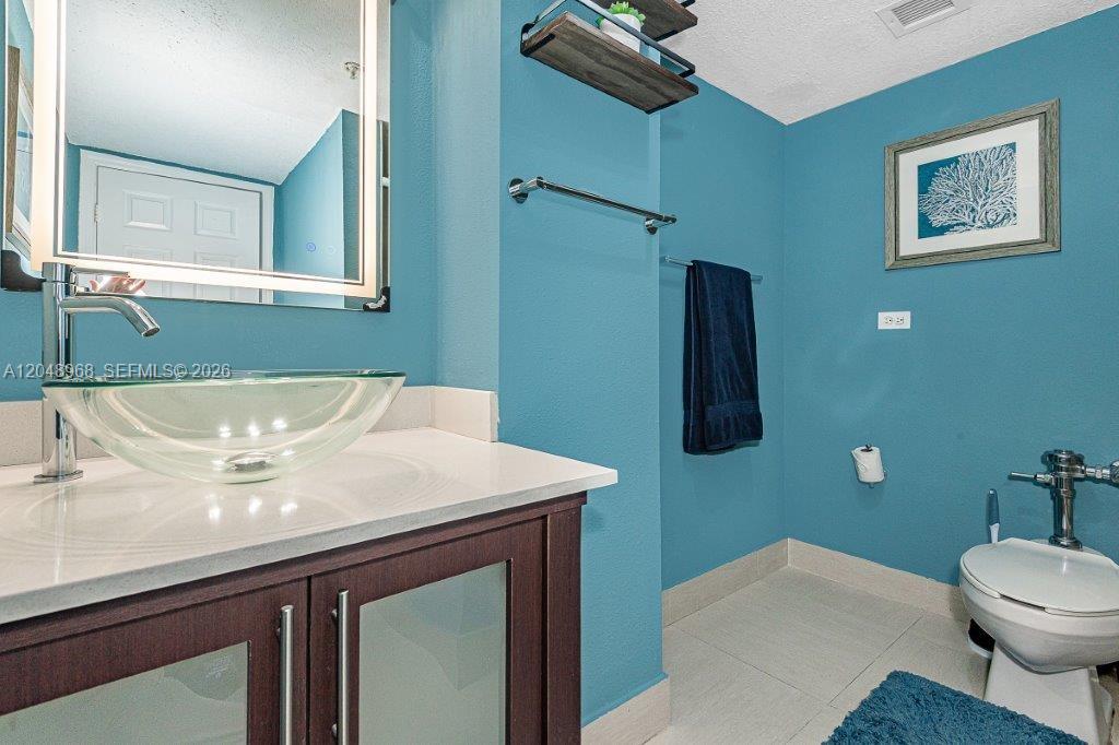 A bathroom features a glass vessel sink, dark wood vanity, and bright blue walls — 1500 Bay Rd # 128S, Miami Beach FL 33139, MIAMI BEACH, FL