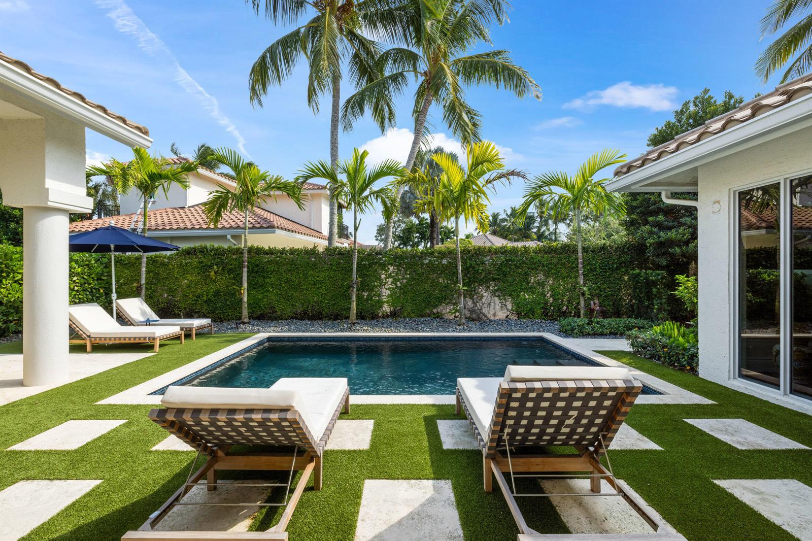 A backyard swimming pool with lounge chairs on a turf patio surrounded by palm trees — 14270 Calypso Lane, Wellington FL 33414, WELLINGTON, FL