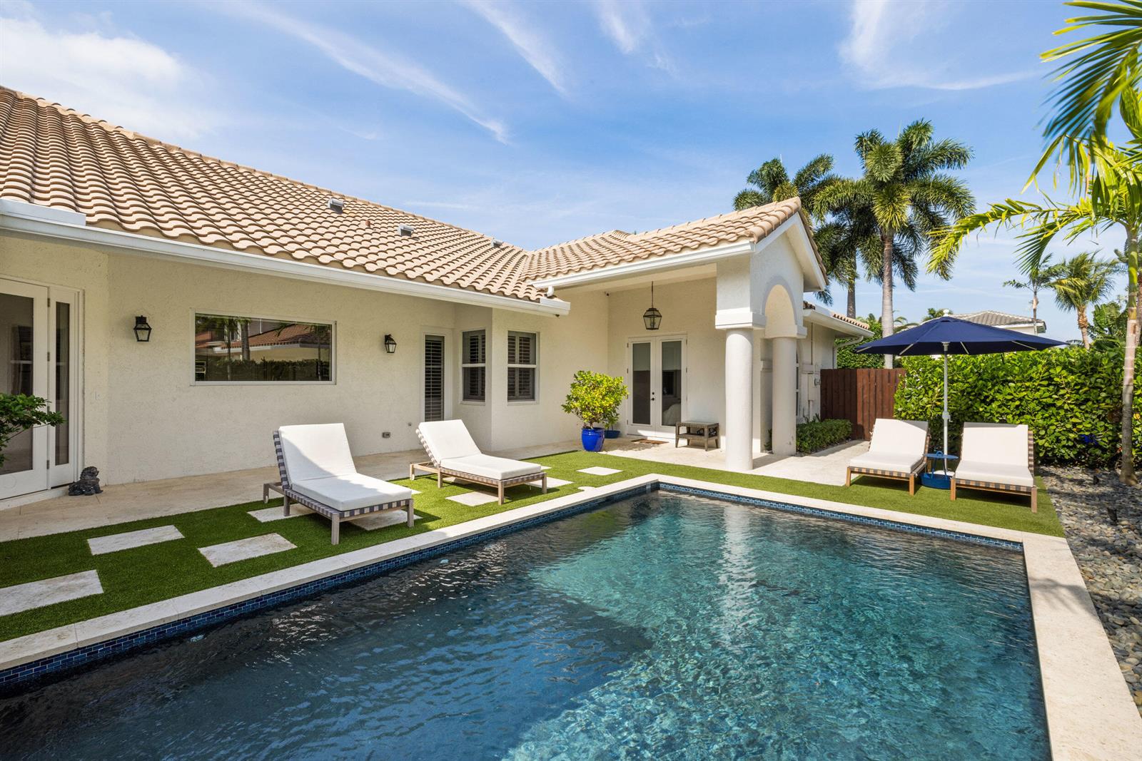 A swimming pool sits in front of a house with a patio and lounge chairs — 14270 Calypso Lane, Wellington FL 33414, WELLINGTON, FL