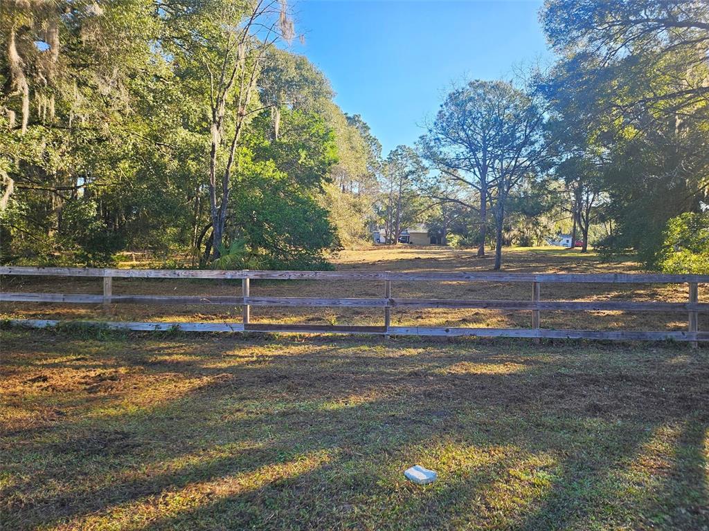 A wooden fence separates a grassy foreground from a wooded lot with a distant house — HAZEN ROAD, DELAND, FL
