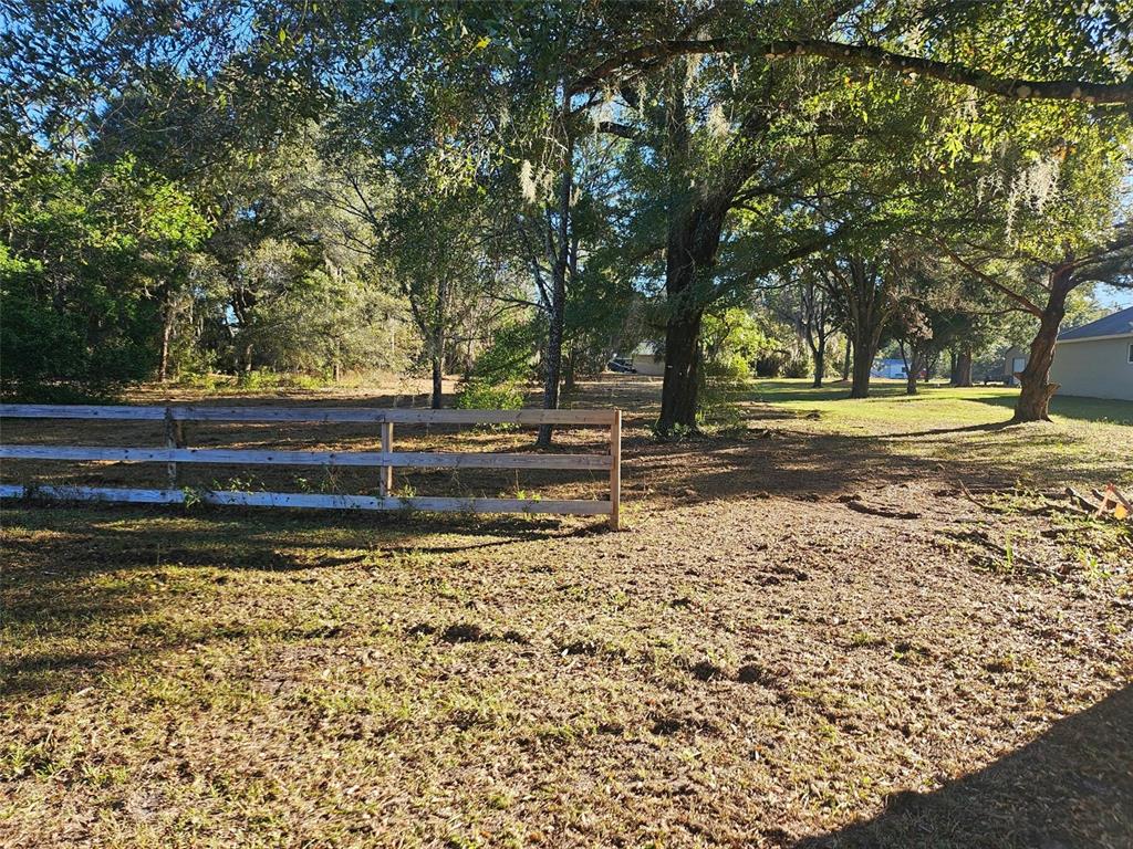 A wooden fence borders a grassy yard shaded by large, mature trees — HAZEN ROAD, DELAND, FL