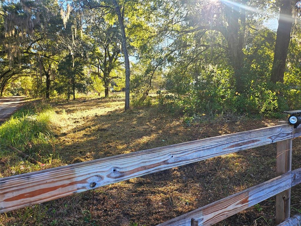 A wooden split-rail fence borders a grassy, tree-filled lot on a sunny day — HAZEN ROAD, DELAND, FL