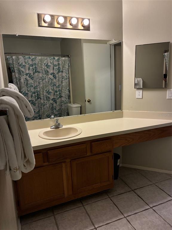 A bathroom features a wooden vanity, a large mirror, and a separate smaller wall mirror — 5433 LAKE MARGARET DRIVE UNIT E 195, ORLANDO, FL