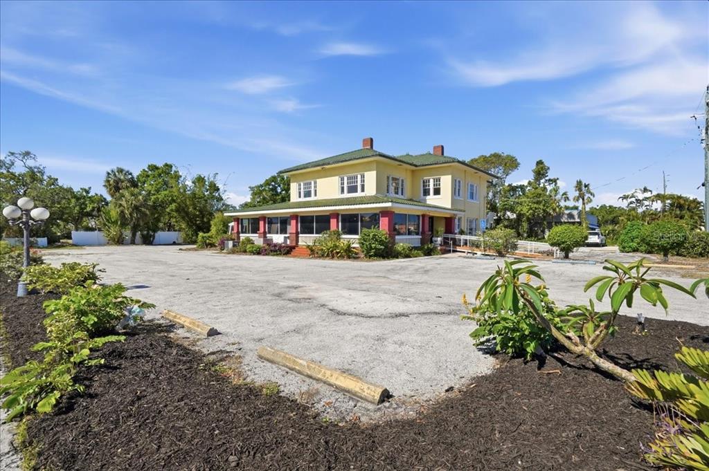 A yellow two-story building with a green roof sits behind a large paved parking lot — 337 8TH AVENUE W, PALMETTO, FL