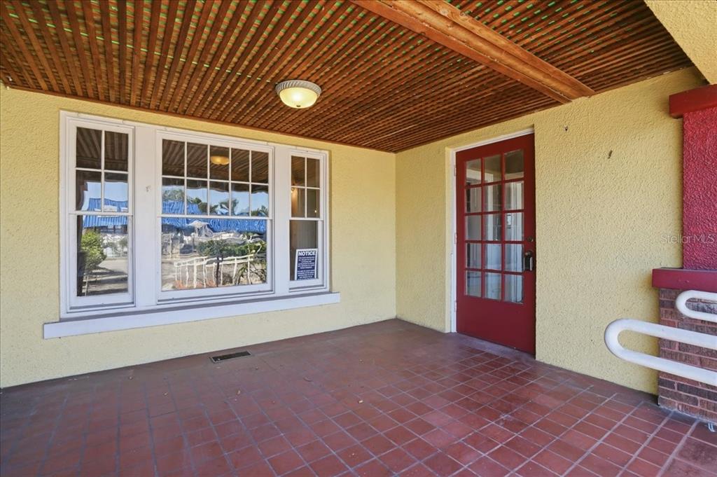 A covered porch with a red door, large windows, and a tiled floor — 337 8TH AVENUE W, PALMETTO, FL