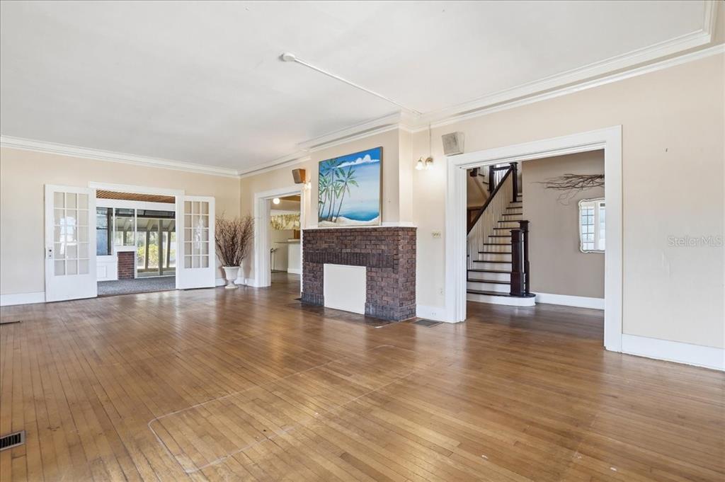 A spacious living room features hardwood floors, a brick fireplace, and a staircase — 337 8TH AVENUE W, PALMETTO, FL