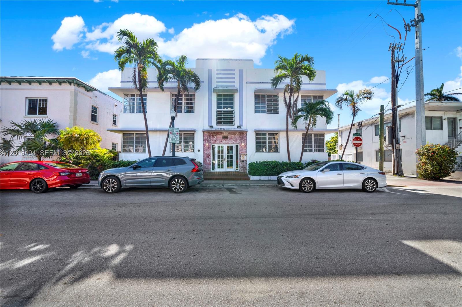 A white Art Deco apartment building stands behind parked cars on a sunny street — 610 8th St # 102, Miami Beach FL 33139, MIAMI BEACH, FL