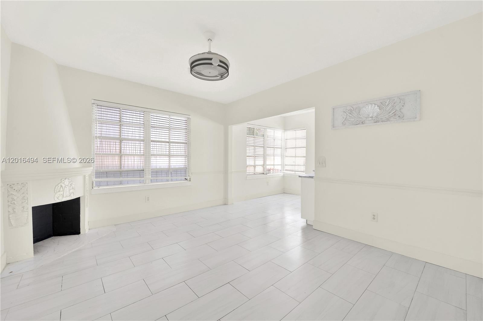 A bright living room features white tile floors, a fireplace, and large windows — 610 8th St # 102, Miami Beach FL 33139, MIAMI BEACH, FL
