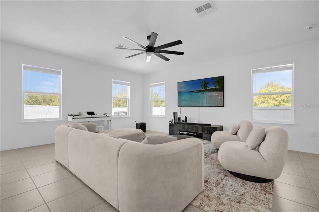 A living room features a large sectional sofa, two armchairs, and a wall-mounted television — 4432 DESERT ROSE AVENUE, KISSIMMEE, FL