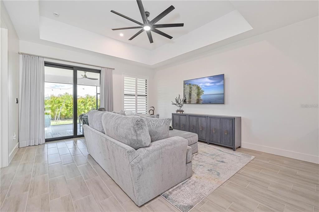 A living room features a grey sectional sofa, a wall-mounted television, and a tray ceiling — 174 MADRID BOULEVARD, PUNTA GORDA, FL