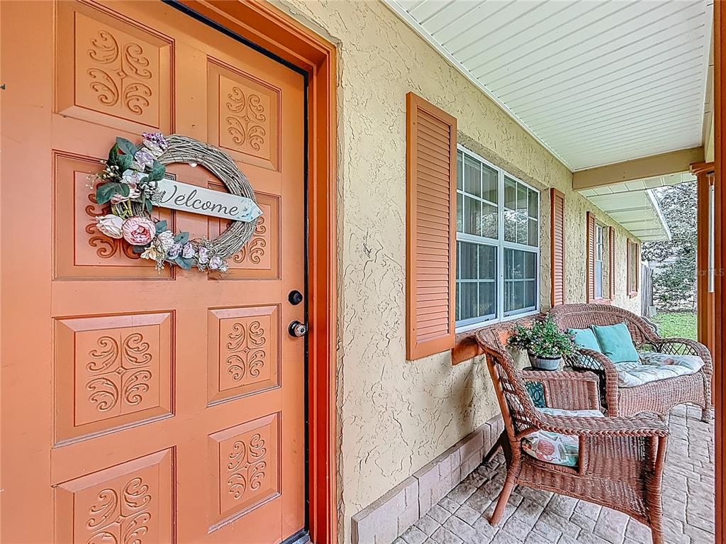 A covered front porch features a peach-colored door, wicker furniture, and a window with shutters — 3301 SE 34TH STREET, OCALA, FL