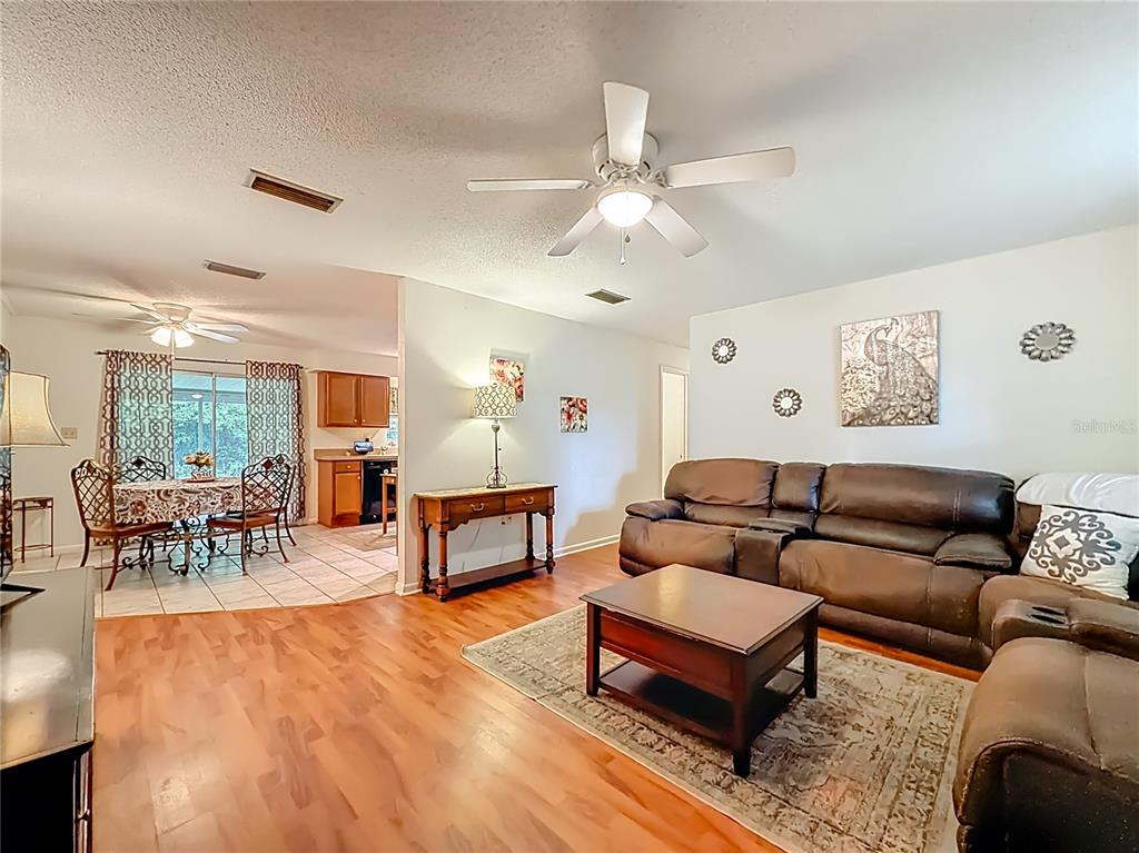A living room with wood flooring, a brown leather sofa, and an adjacent dining area — 3301 SE 34TH STREET, OCALA, FL