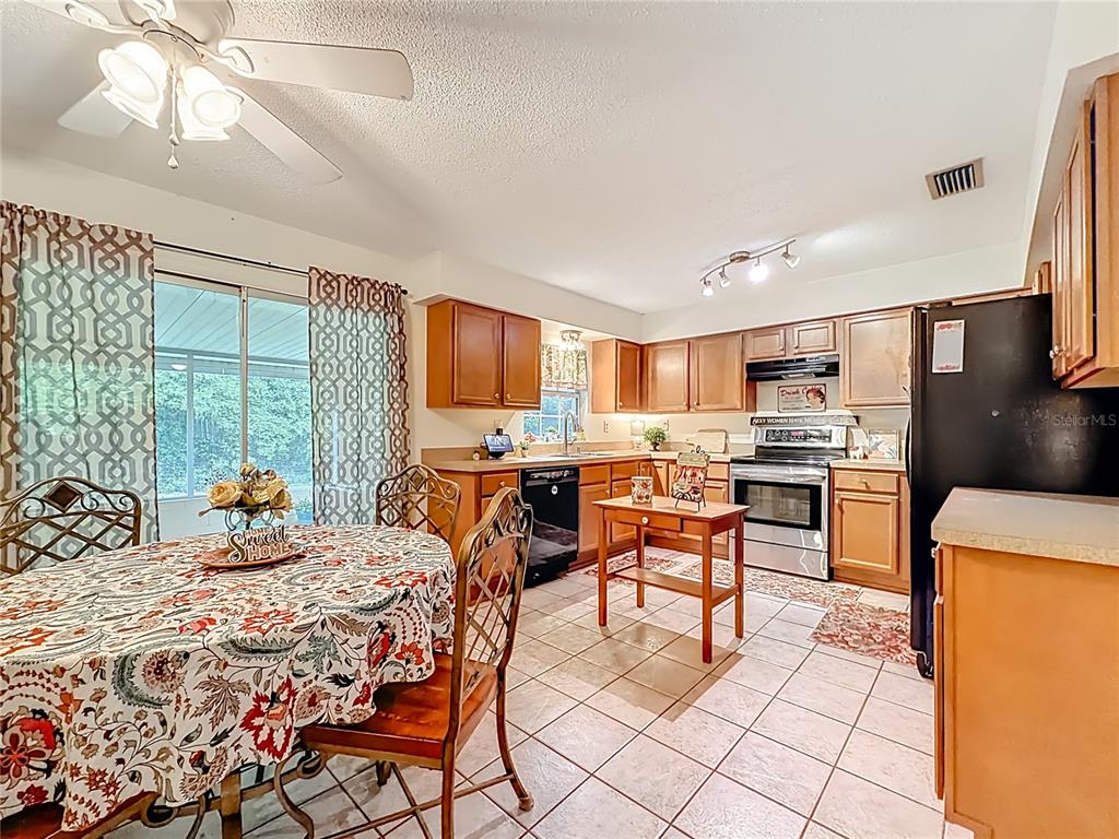 A kitchen and dining area with wood cabinets, tile floors, and a ceiling fan — 3301 SE 34TH STREET, OCALA, FL