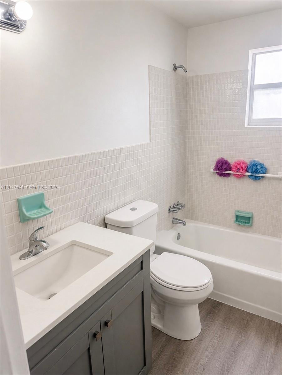 A bathroom features a gray vanity, white toilet, and a tiled shower-tub combination — 685 Miller Dr # E205, Miami Springs FL 33166, MIAMI SPRINGS, FL