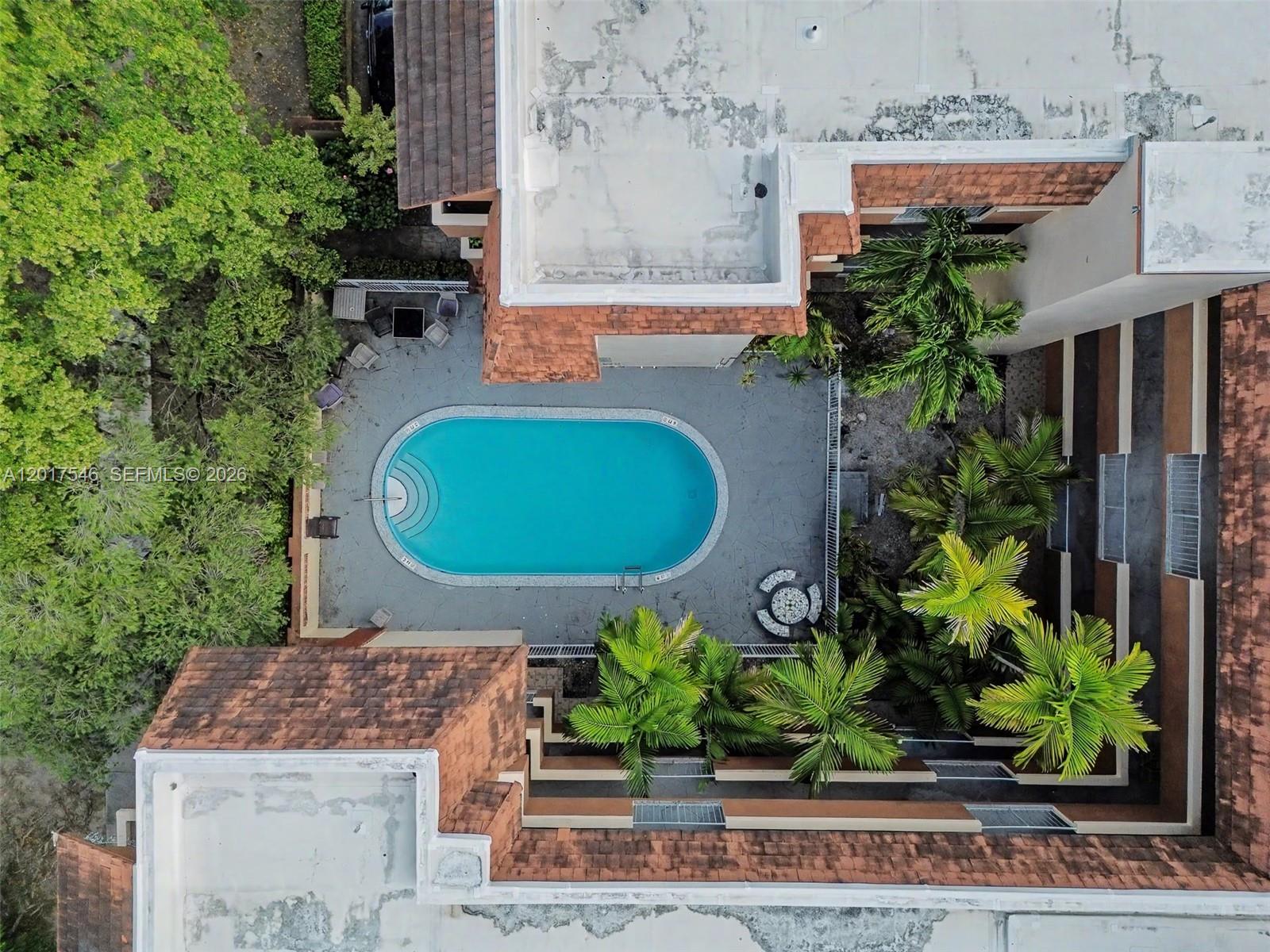 An aerial view shows a swimming pool in a courtyard surrounded by palm trees — 685 Miller Dr # E205, Miami Springs FL 33166, MIAMI SPRINGS, FL