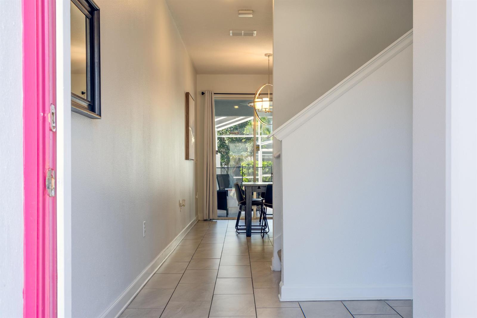A tiled hallway leads past a staircase toward a dining area with a sliding glass door — 650 Pebble Beach Drive, Davenport FL 33896, DAVENPORT, FL