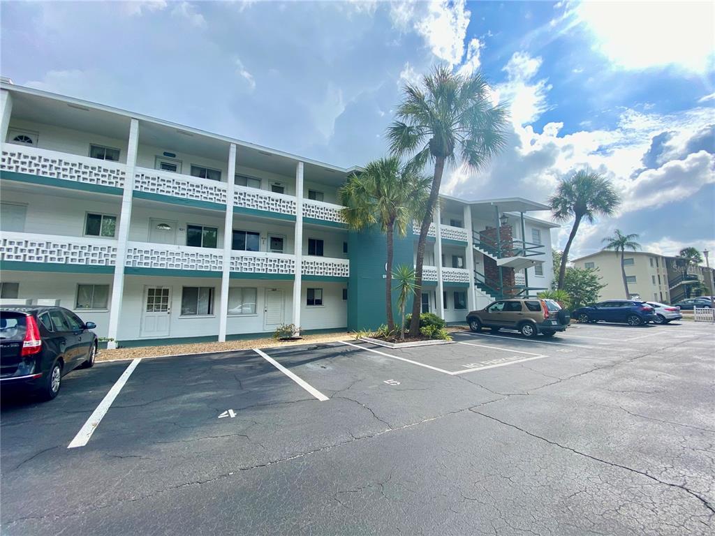 A multi-story apartment building with a parking lot in the foreground and palm trees — 1825 FLAMINGO BOULEVARD UNIT O26, BRADENTON, FL