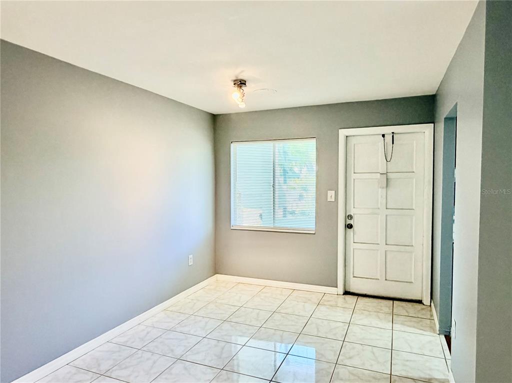 A room with gray walls, white tile flooring, a window with blinds, and a door — 1825 FLAMINGO BOULEVARD UNIT O26, BRADENTON, FL