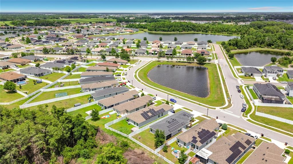 An aerial view shows a suburban neighborhood with houses, white fences, and two retention ponds — 3040 LAKES CREST AVENUE, ST CLOUD, FL
