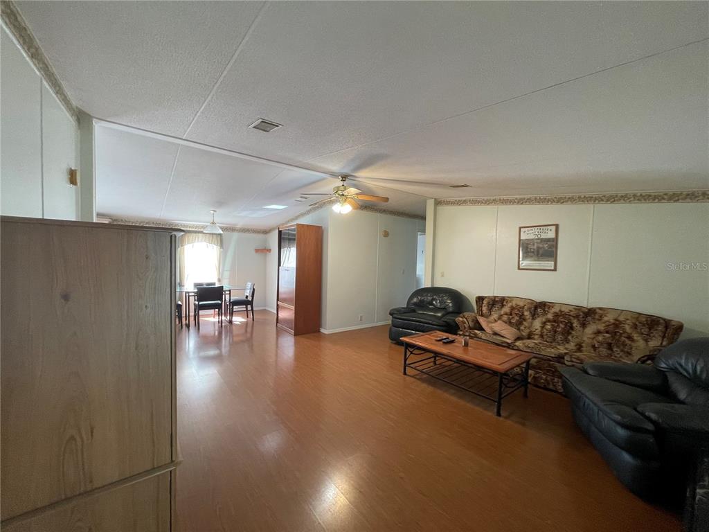 A living room with wood-look flooring, a ceiling fan, and a patterned sofa — 1550 SE 111TH COURT, MORRISTON, FL