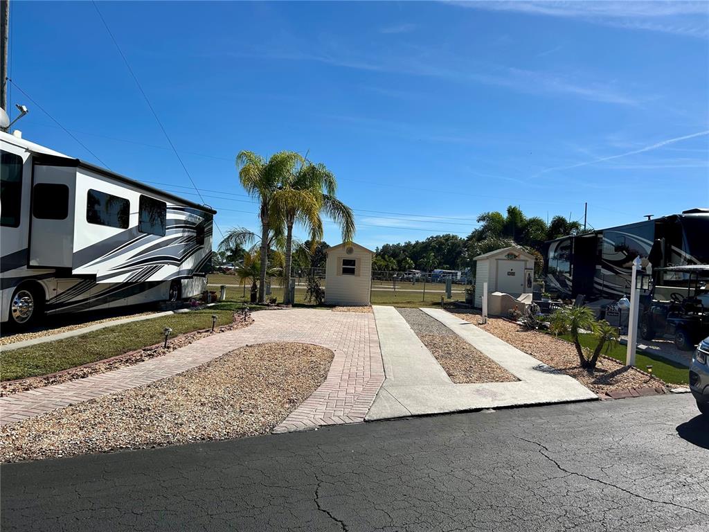 An outdoor RV site features a paved driveway, two storage sheds, and palm trees — 2920 FAIRWAY DRIVE, BOWLING GREEN, FL