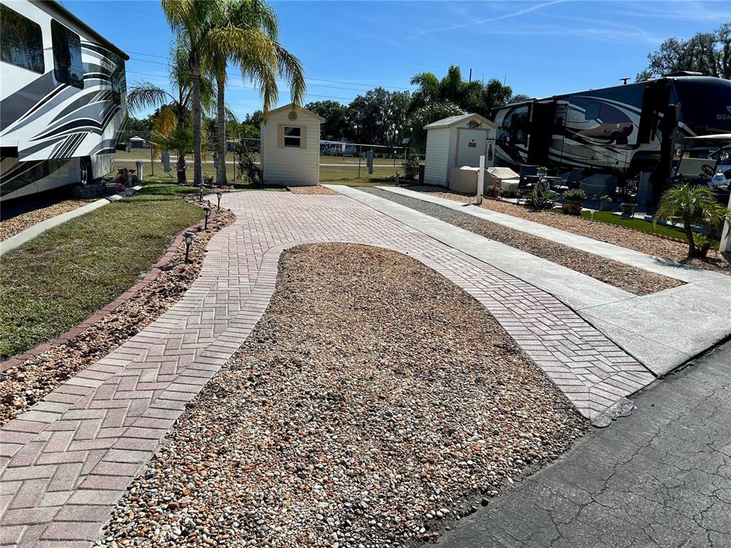 A paved driveway with a gravel center island sits between two RVs and storage sheds — 2920 FAIRWAY DRIVE, BOWLING GREEN, FL