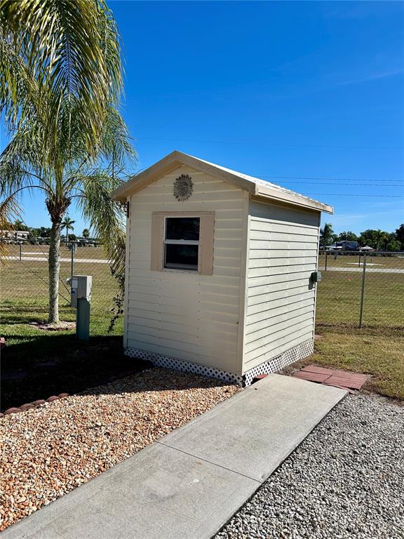 A small, light-colored storage shed sits on a gravel lot next to a concrete walkway — 2920 FAIRWAY DRIVE, BOWLING GREEN, FL