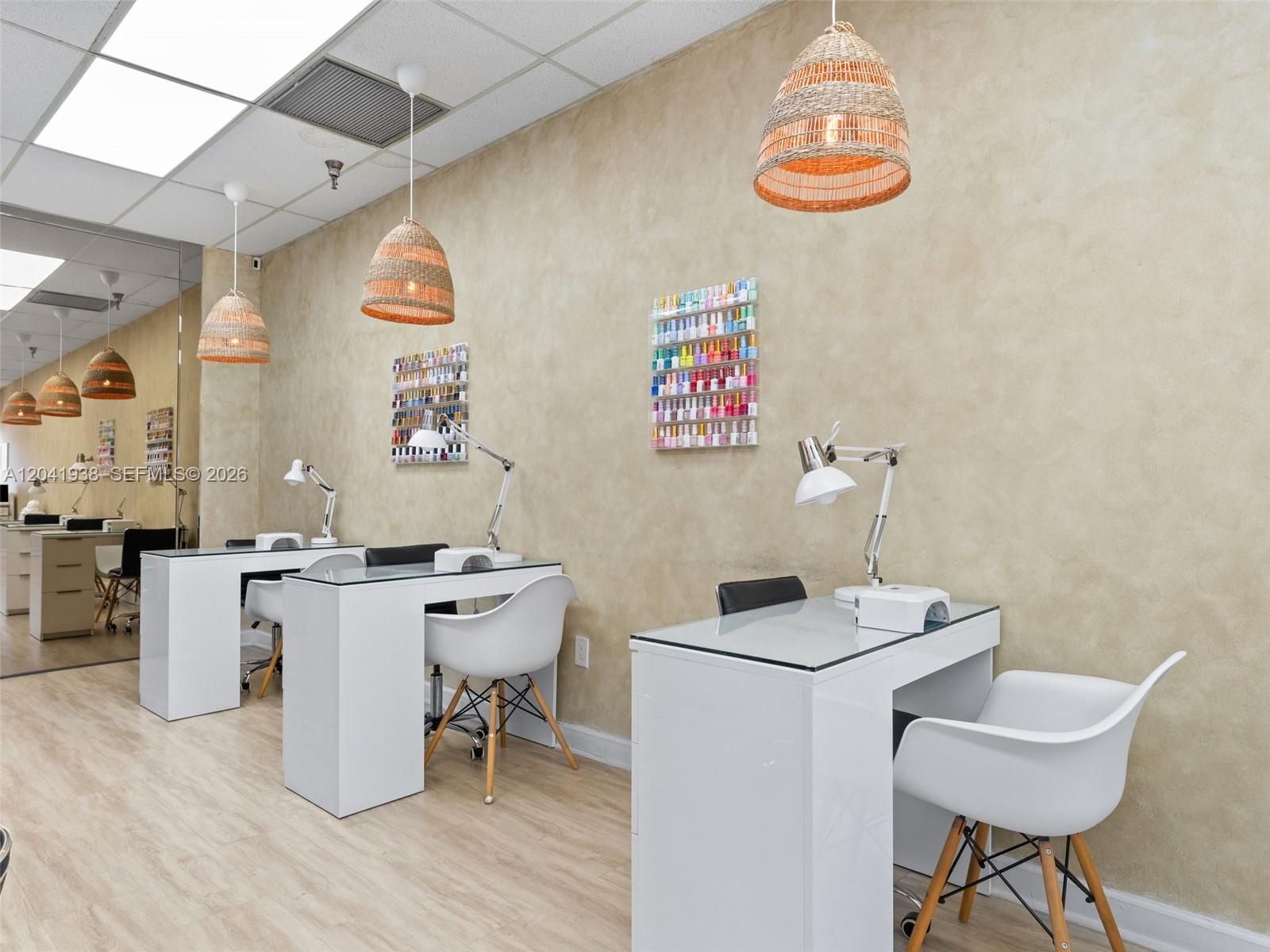 A nail salon features three white manicure stations with chairs and wall-mounted polish racks — MIAMI, FL