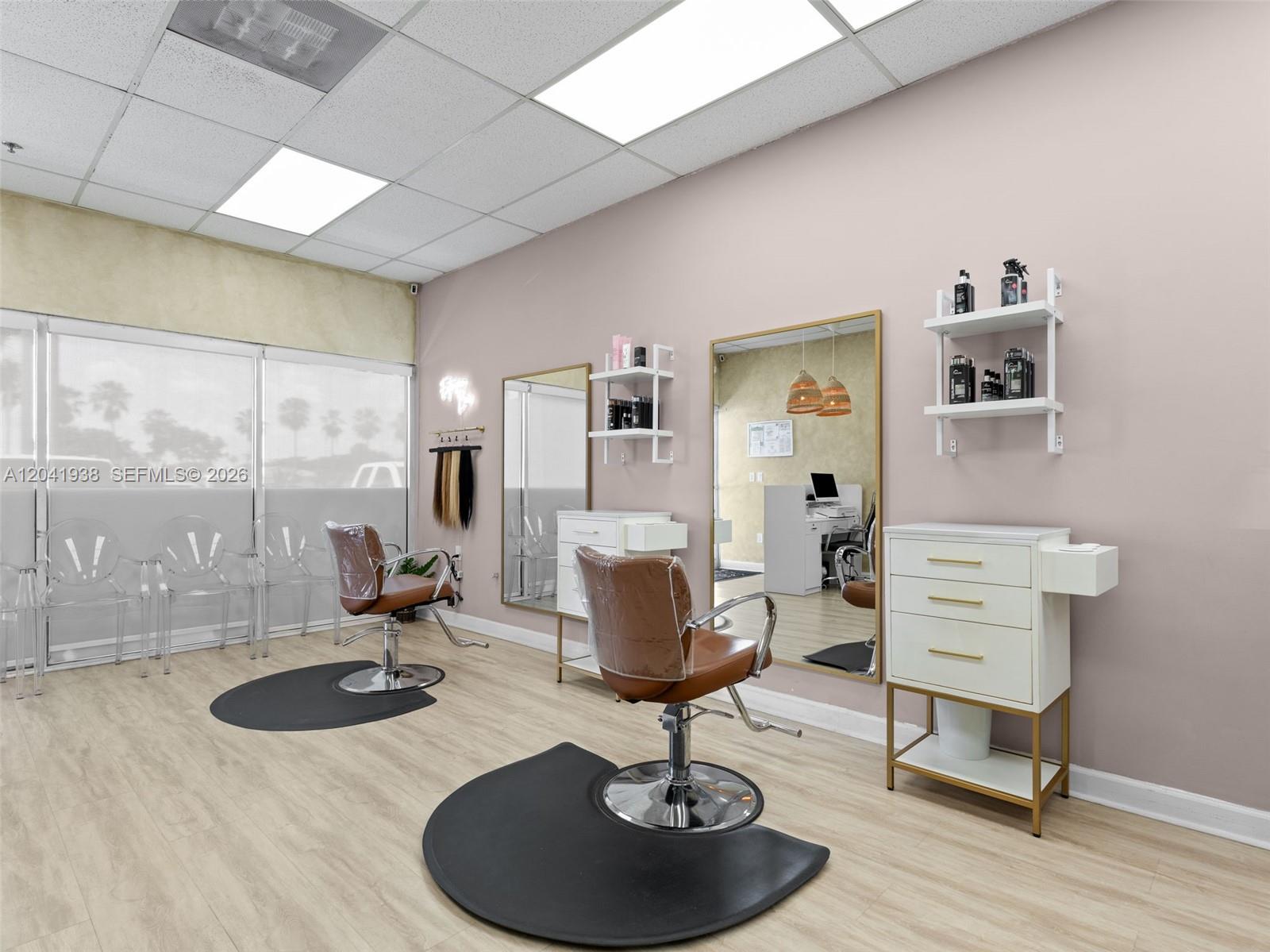 A hair salon features two styling stations with brown chairs, mirrors, and white storage cabinets — MIAMI, FL
