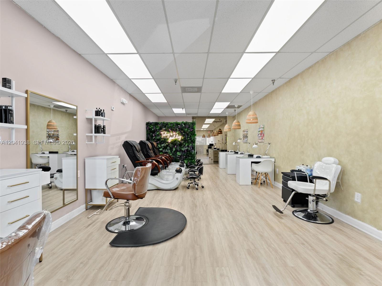 A bright salon interior features pedicure chairs, manicure stations, styling chairs, and light wood flooring — MIAMI, FL