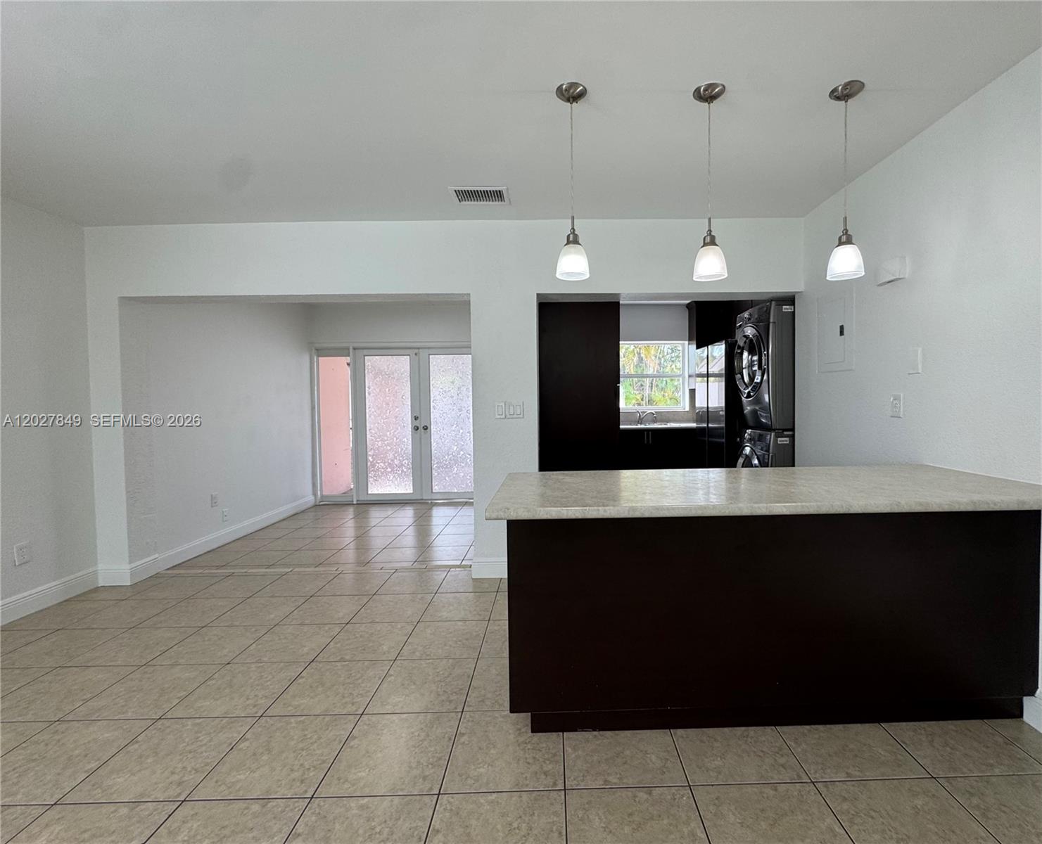 A kitchen with a dark island and pendant lights opens to a tiled living area — 7420 Big Cypress Dr, Miami Lakes FL 33014, MIAMI LAKES, FL