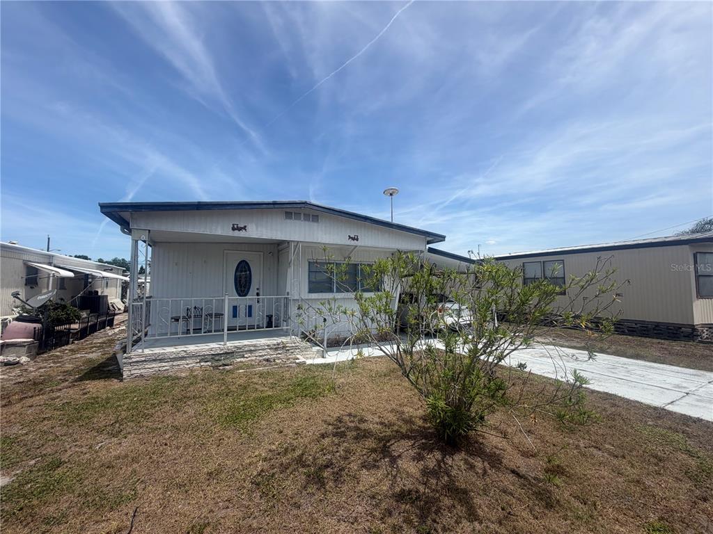 A single-story manufactured home features a front porch, white siding, and a paved driveway — 3020 SEGO LANE, LAKELAND, FL