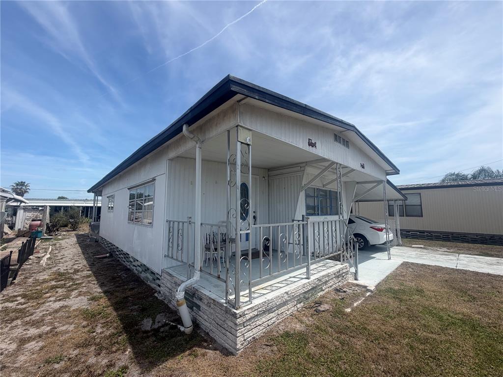 An exterior view of a white mobile home featuring a front porch and carport — 3020 SEGO LANE, LAKELAND, FL