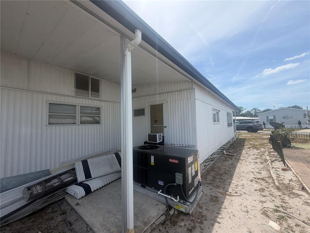The exterior of a mobile home features a concrete patio, a Goodman HVAC unit, and siding — 3020 SEGO LANE, LAKELAND, FL